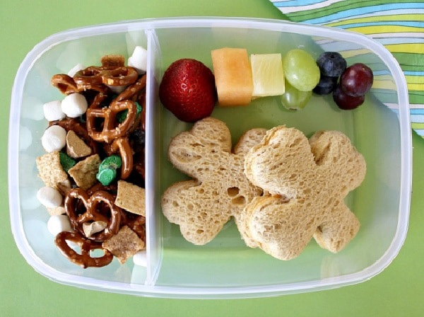 a st patricks day lunch box for kids with shamrock shaped sandwiches, a rainbow of fruit, and snack mix