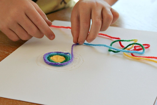 yarn scraps being wound on paper with glue to make a snail shell