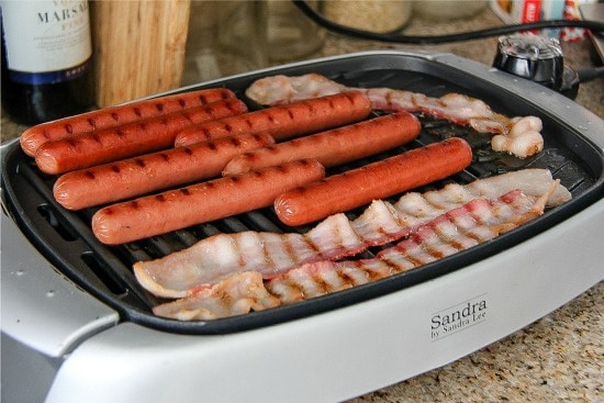 hot dogs and bacon cooking on an indoor grill