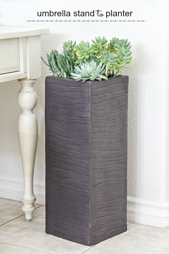a large umbrella stand turned into a succulent planter for an entryway