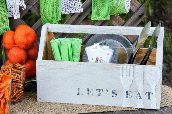 a wood crate with napkins and utensils for a party