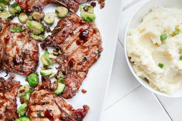 pork chops with barbecue sauce and brussels sprouts with a bowl of mashed potatoes
