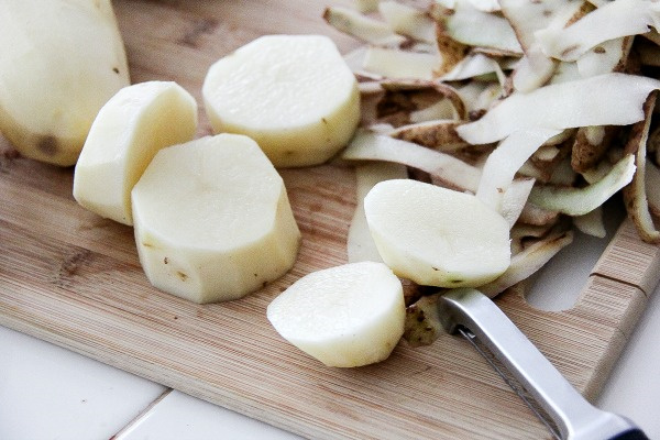 potatoes peeled and sliced on a cutting board