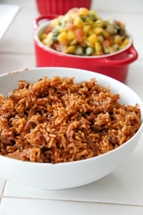 mexican rice in a white bowl and salsa in a red bowl