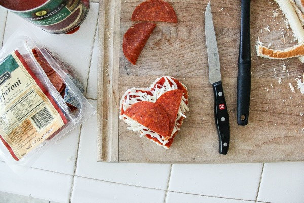 pepperoni and cheese heart shaped pizzas being made