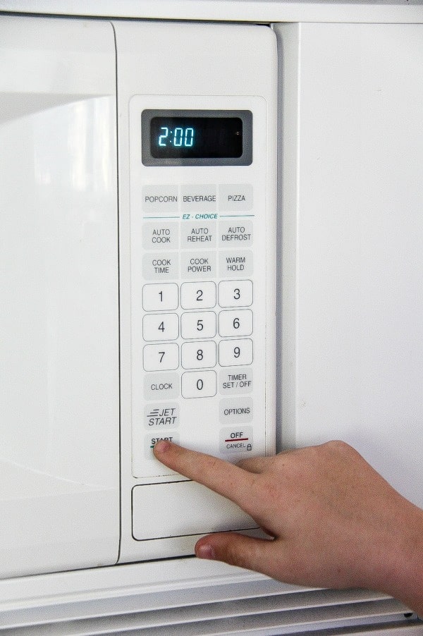 a person pressing buttons on a microwave