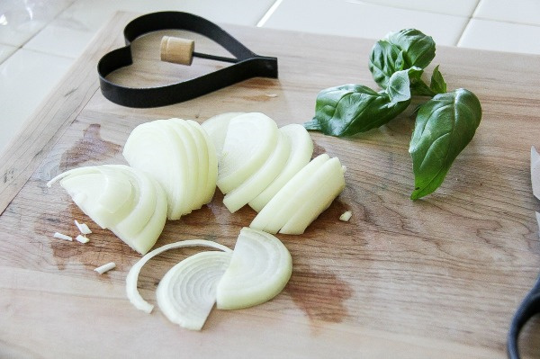 sliced onion and fresh basil on a cutting board