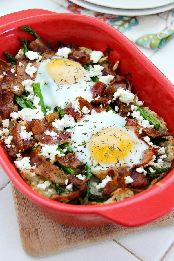 a casserole dish with baked eggs, bacon, asparagus