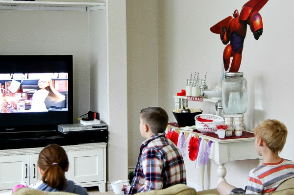 a big hero 6 movie night set up with kids watching the movie and a food table