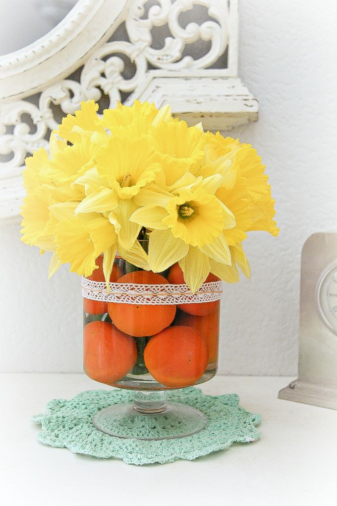 citrus floral arrangement in a vase using mandarins and daffodils