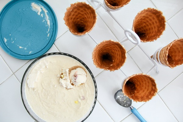 peanut butter ice cream in a tub next to waffle cones