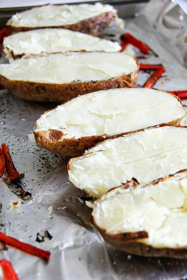 baked potatoes sliced in half on a baking tray