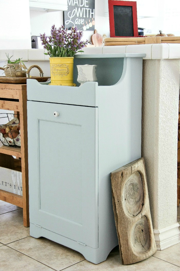 a wood trash can cabinet inside a kitchen