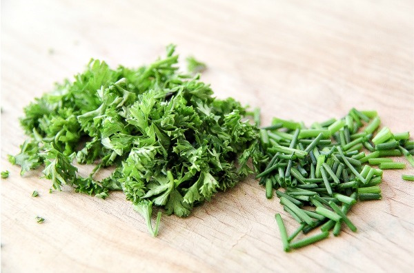 chives and parsley on a cutting board