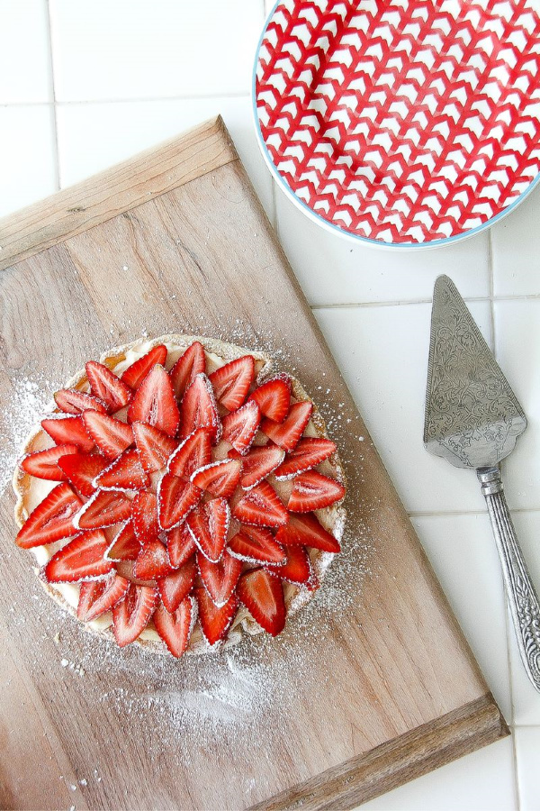 a strawberry cheesecake on a cutting board with plates