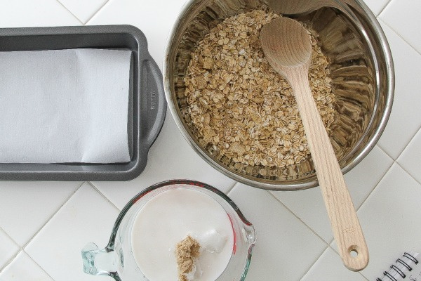 a bowl of oats, a lined baking pan, and a cup of sugar