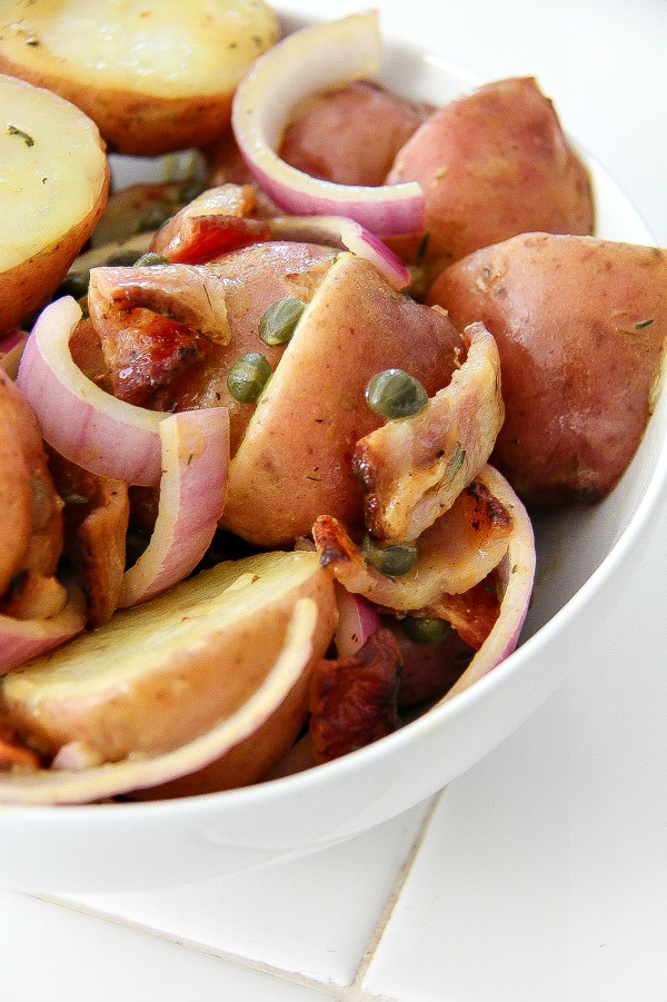 red potato salad with bacon and red onions in a bowl