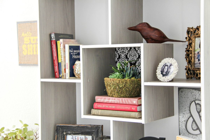 square shelving with books, frames, and a plant