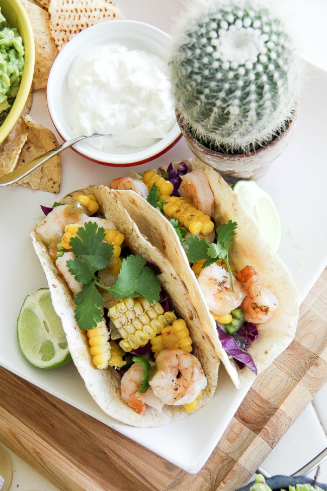 shrimp and corn tacos with a bowl of sour cream