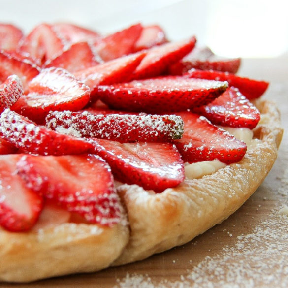 a strawberry cheesecake tart on a wood board