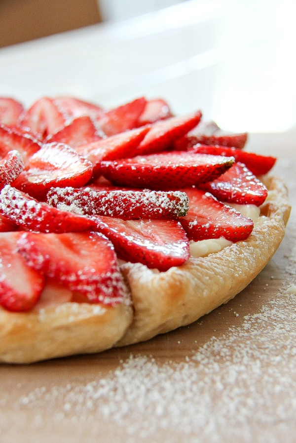 a strawberry cheesecake tart on a wood board