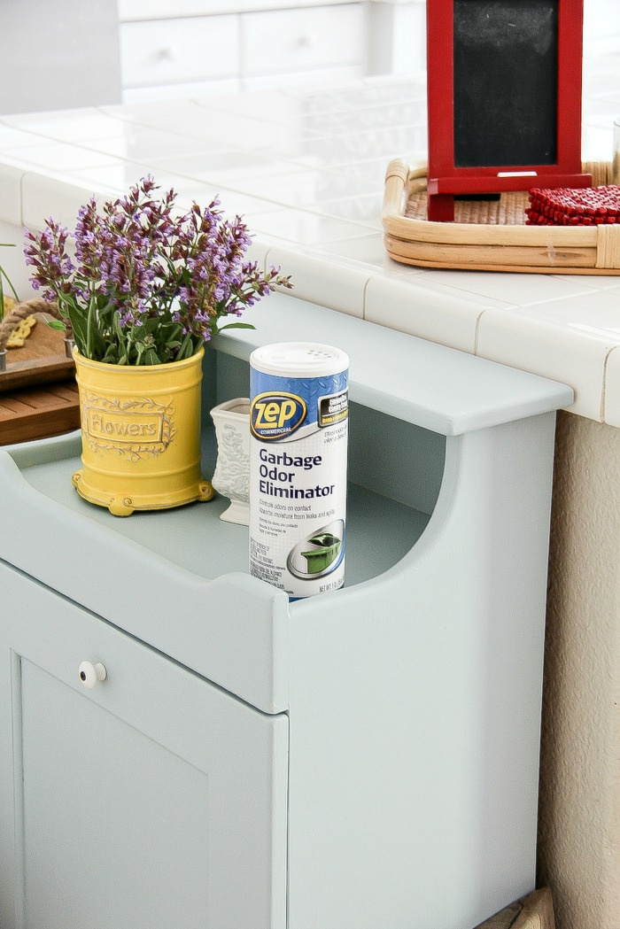 zep garbage odor eliminator on top of a wood trash can cabinet