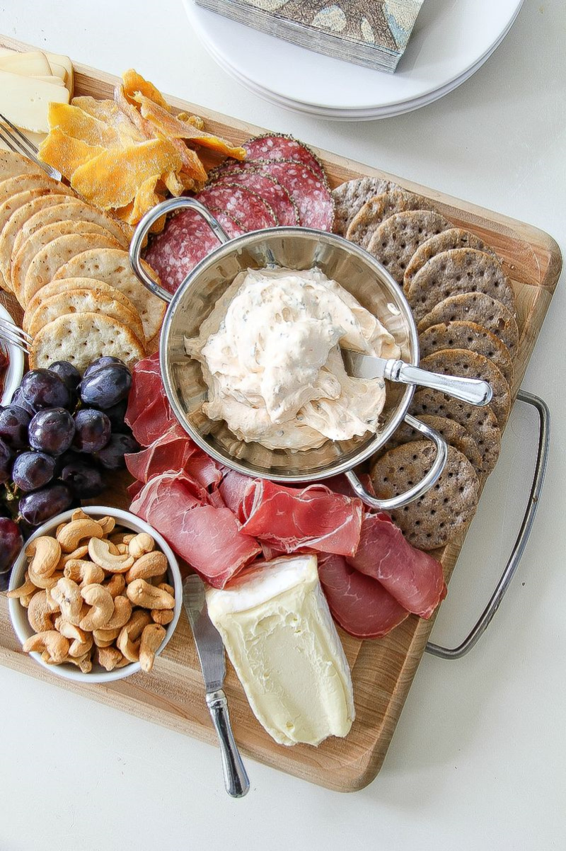 a grazing board with nuts, meats, cheese and fruit.