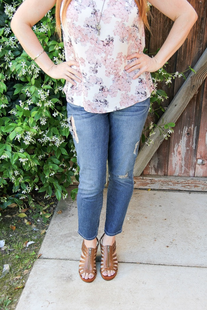 woman wearing denim jeans with brown sandals and a pastel floral top