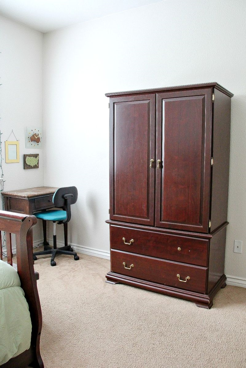 a dark wood armoire with missing drawer pulls