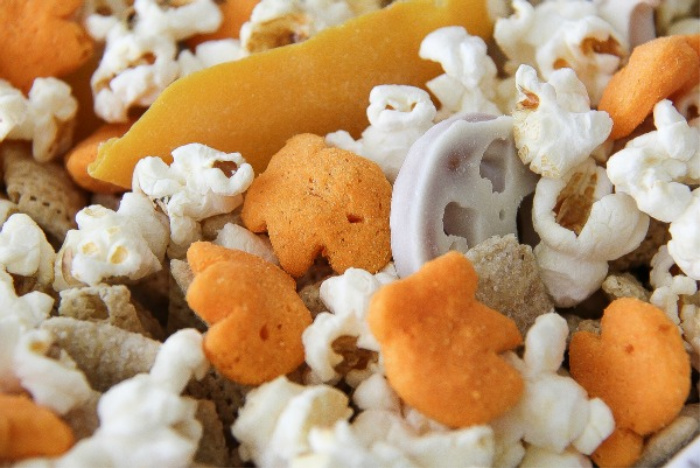 goldfish puffs, popcorn and yogurt covered pretzels in a bowl