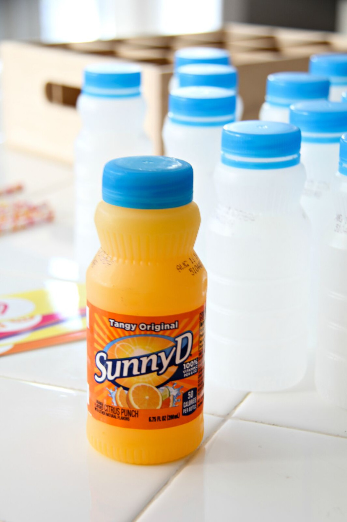 a bottle of SunnyD with more empty bottles with the labels removed