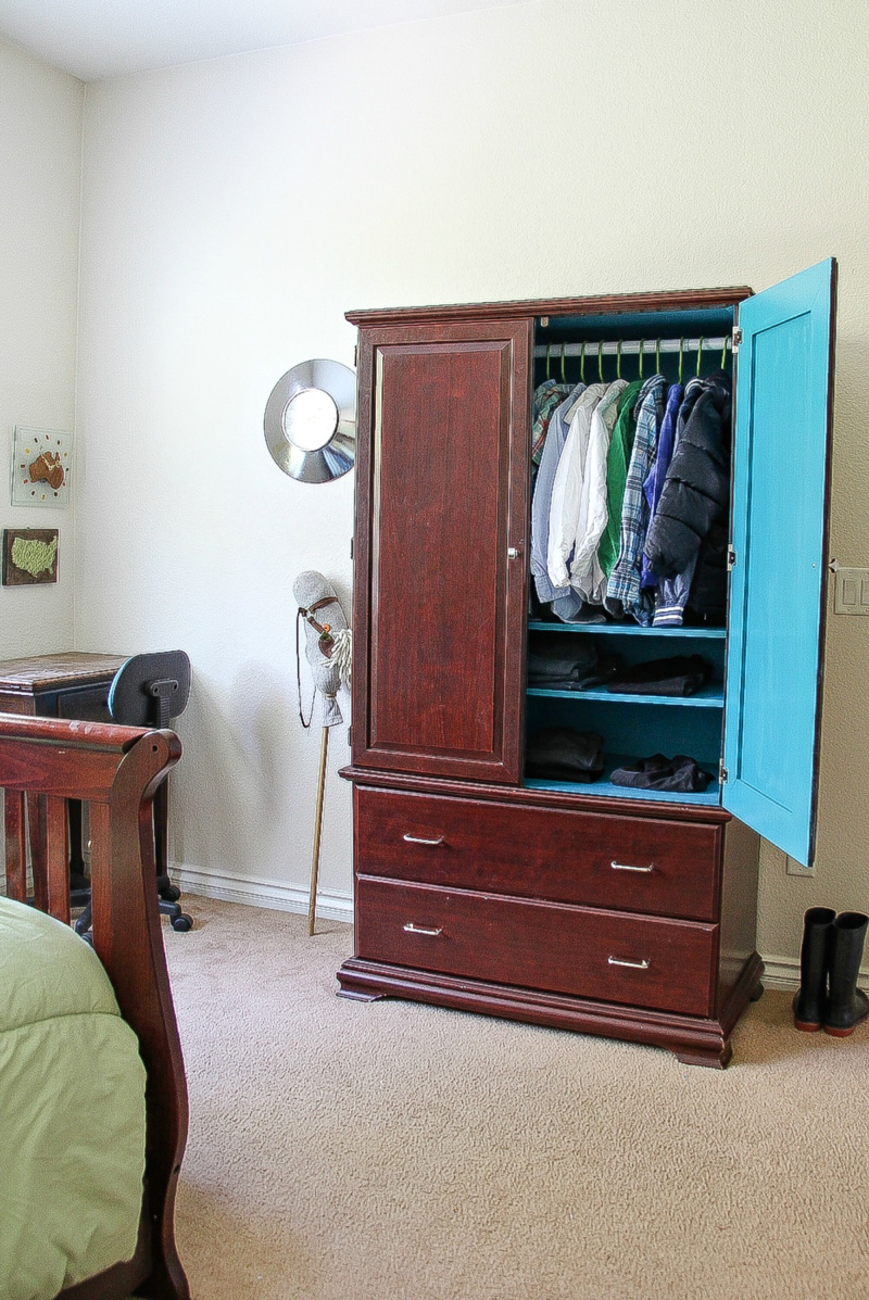 a dark wood armoire in a boys bedroom 