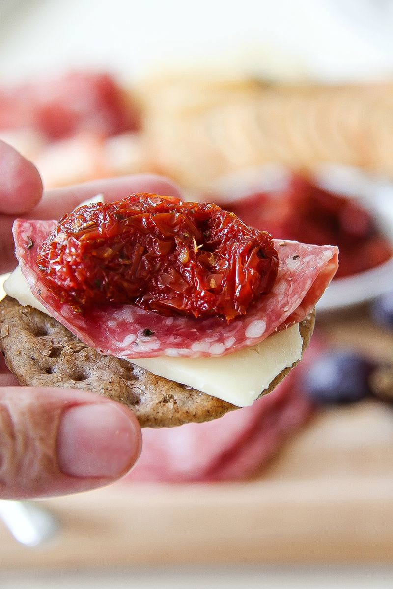 sundried tomato with salami and cheese on a cracker