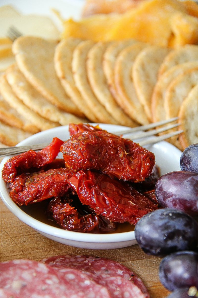 sundried tomatoes in a white dish on a charcuterie board