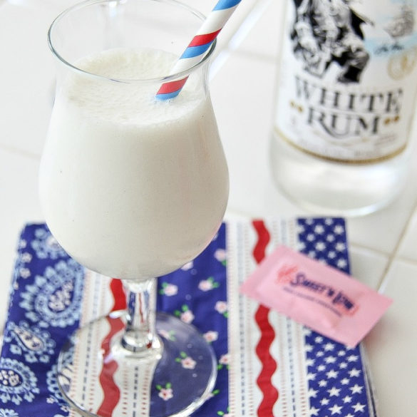 a white milkshake in a glass with a bottle of white rum