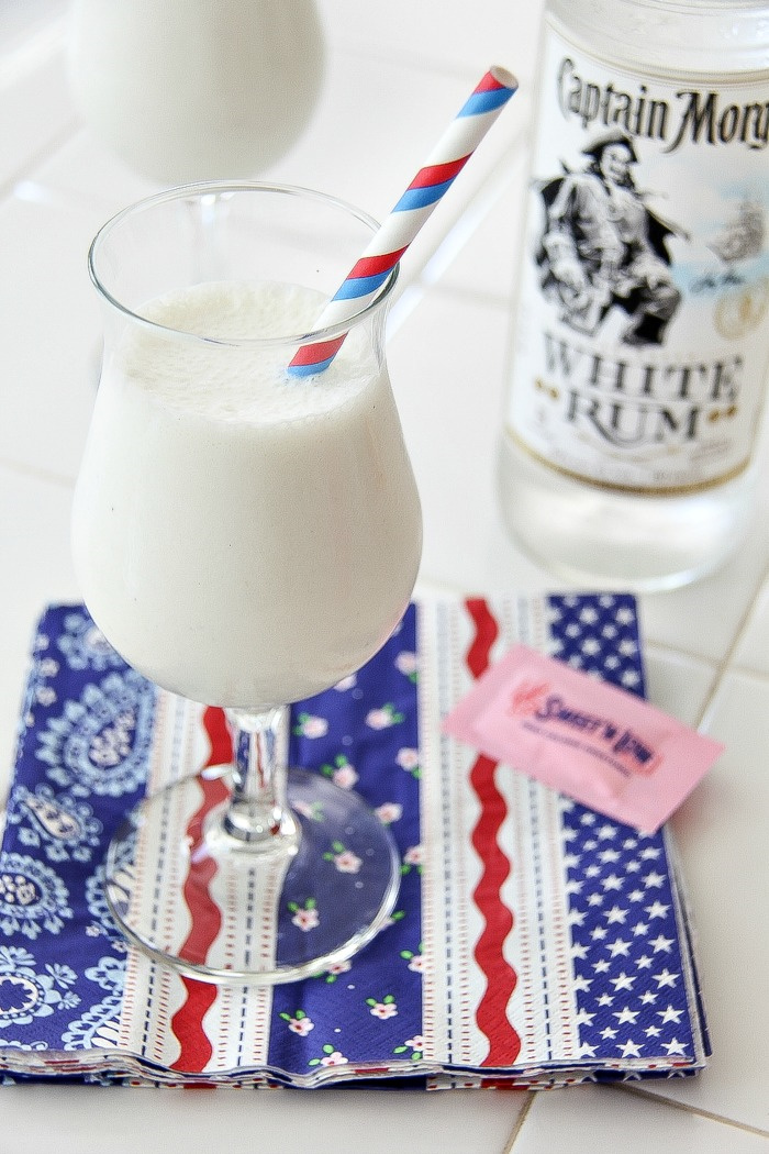 a white milkshake in a glass with a bottle of white rum