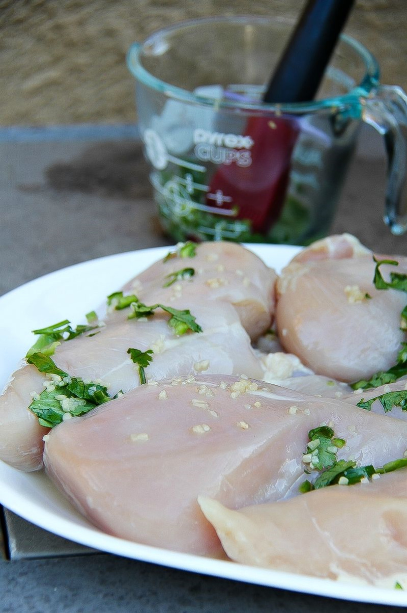 chicken ready to go on the grill with cilantro and serrano chili on top