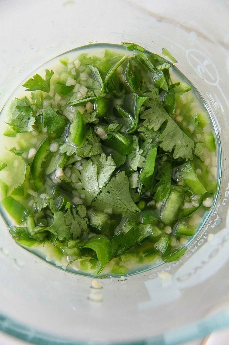 cilantro, serrano chili in a cup with liquid to make a marinade