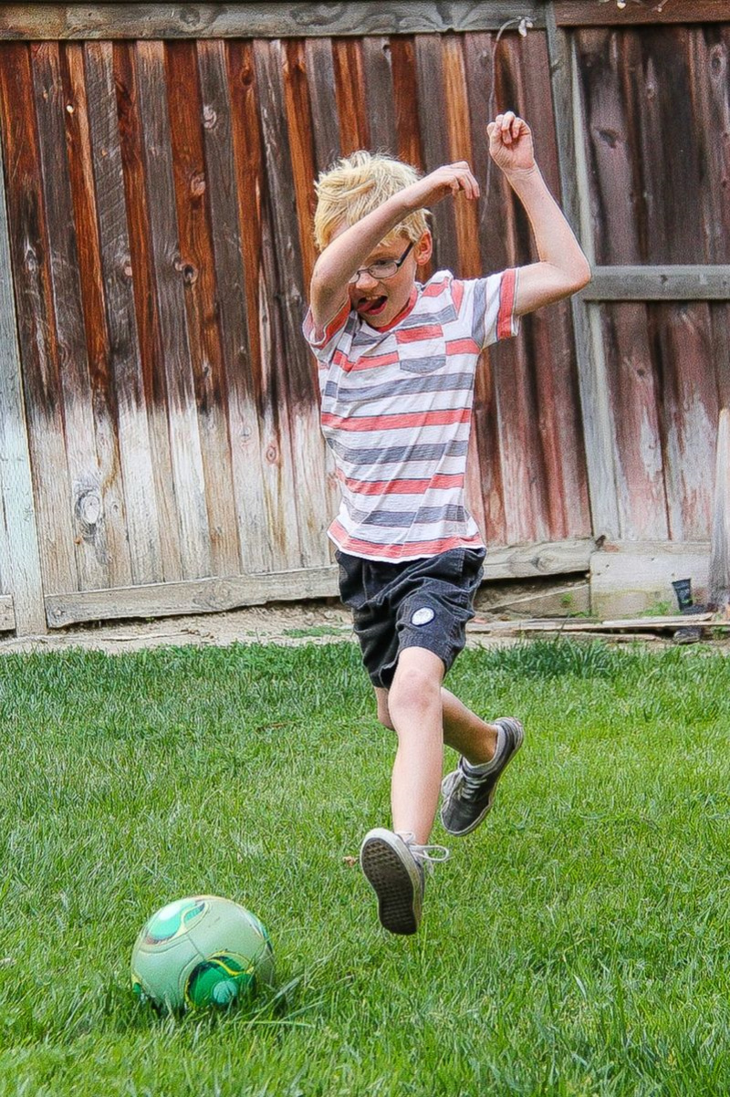 a boy kicking a soccer ball in the backyard