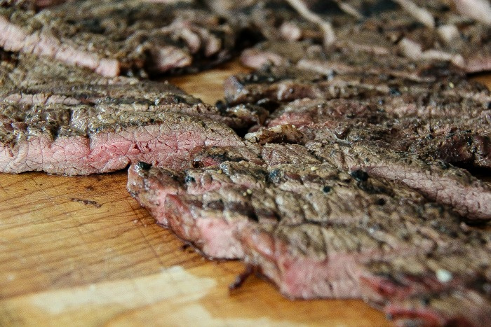 grilled steak cut into thin slices on a cutting board