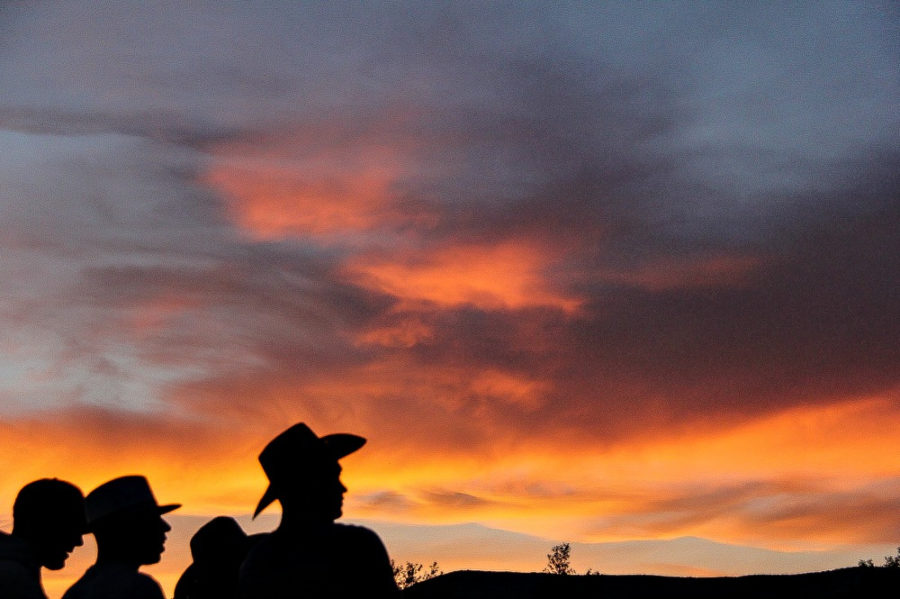 silhouettes of men in various hats with the sunset in the background