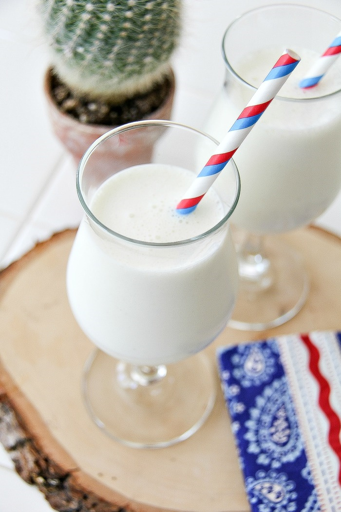 white chocolate vanilla milkshake in a glass with blue red and white napkin and straw