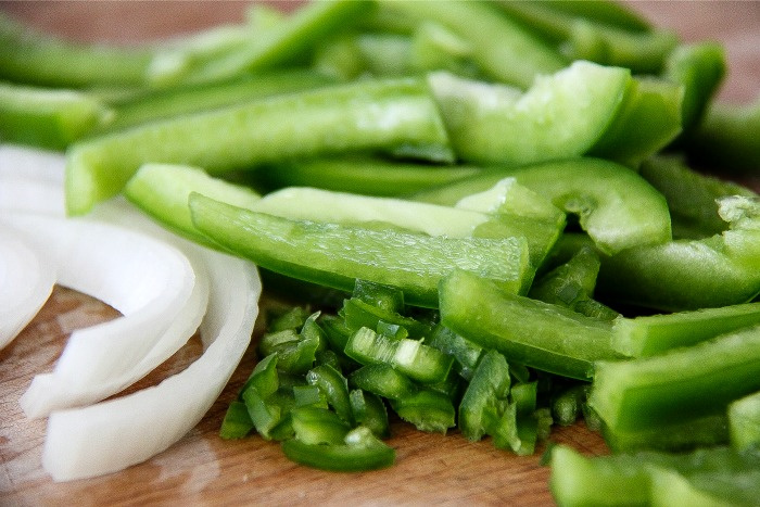 green peppers, jalapeno, and onion on a cutting board