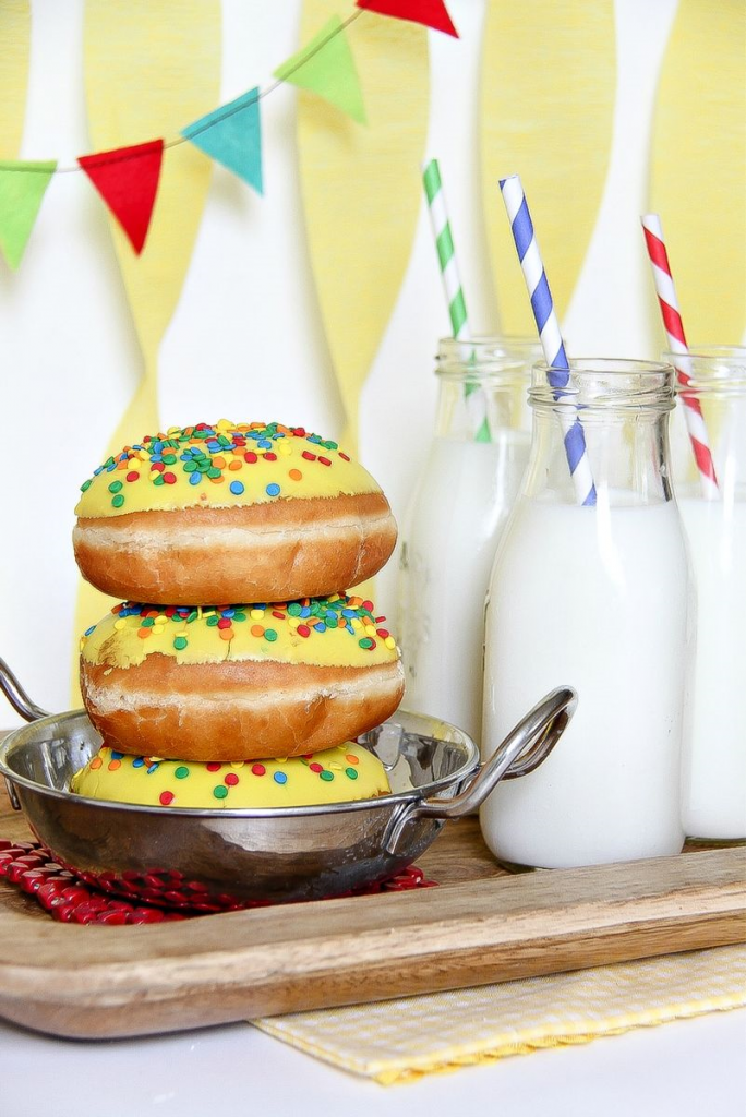 donuts on a silver dish with milk bottles and straws in front of a birthday banner