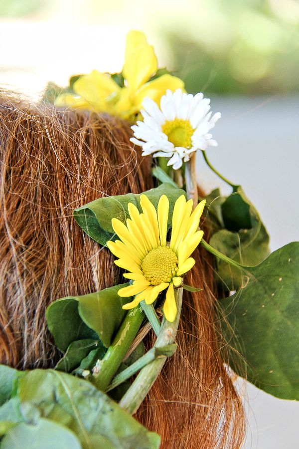 a yellow and white fresh flower crown on a girls head