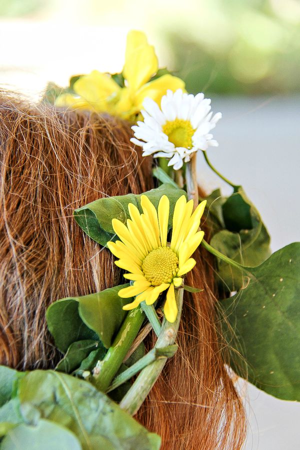 a yellow and white fresh flower crown on a girls head