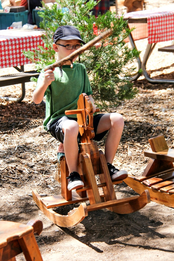 boy riding a small wooden hobby horse and holding a stick