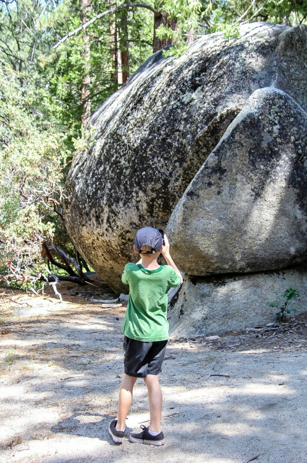 boy taking a photo of a boulder