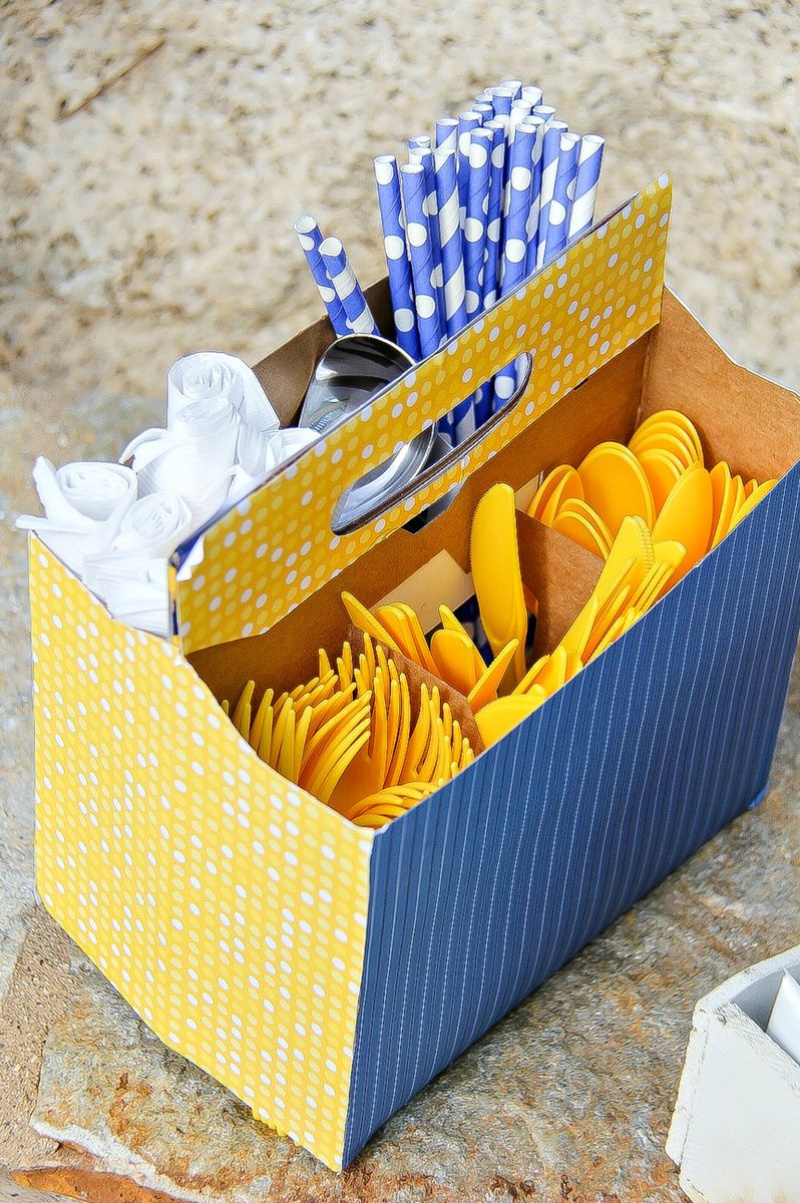 a yellow and blue utensil caddy filled with napkins, straws, and utensils