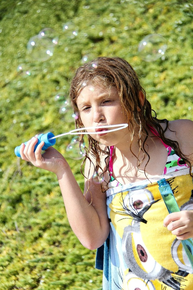 a girl using a bubble wand to blow bubbles